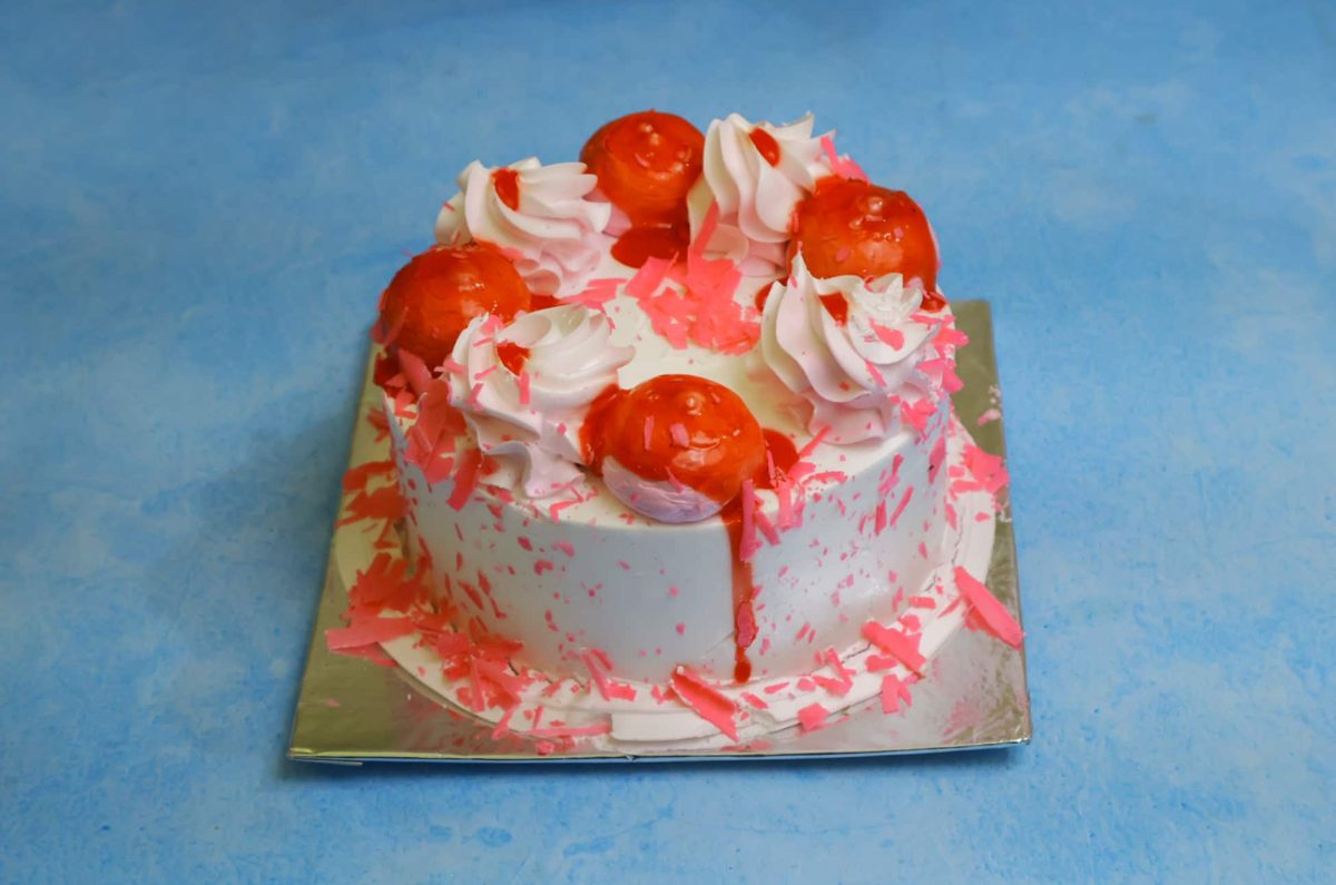 White cream cake with strawberry glaze and pink chocolate shavings